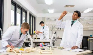 現代化科學實驗室：兩名身穿白袍的高中學生正專注地進行化學試管實驗。BBC 常年名列昆州 ATAR 升學前茅，為學生奠定邁向澳洲八大名校醫學院與工程系堅實基礎。
